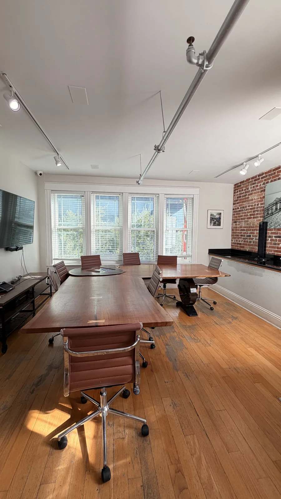 A conference room with a long wood table and a row of windows, on the 4th floor of our building at 433 Central Ave, St. Petersburg