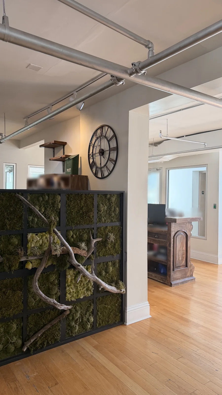 The 4th-floor lobby in our building at 433 Central Ave, St. Petersburg, with a moss wall, a wall clock and a wooden reception desk