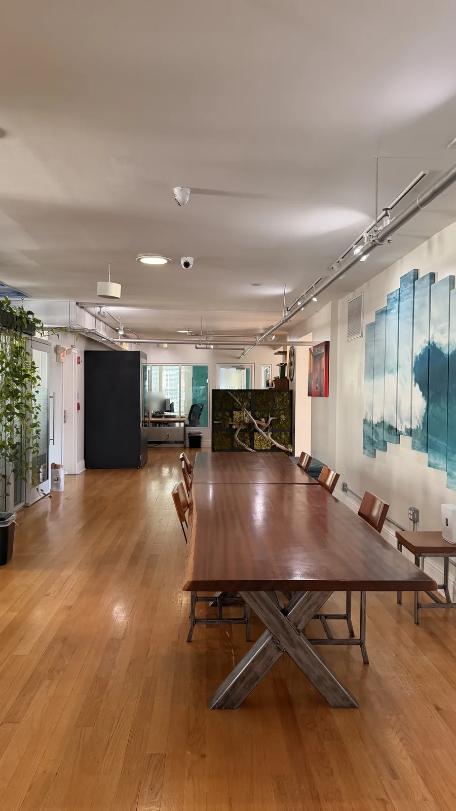 An open work area with a long wood table and wave artwork, on the 4th floor of our building at 433 Central Ave, St. Petersburg