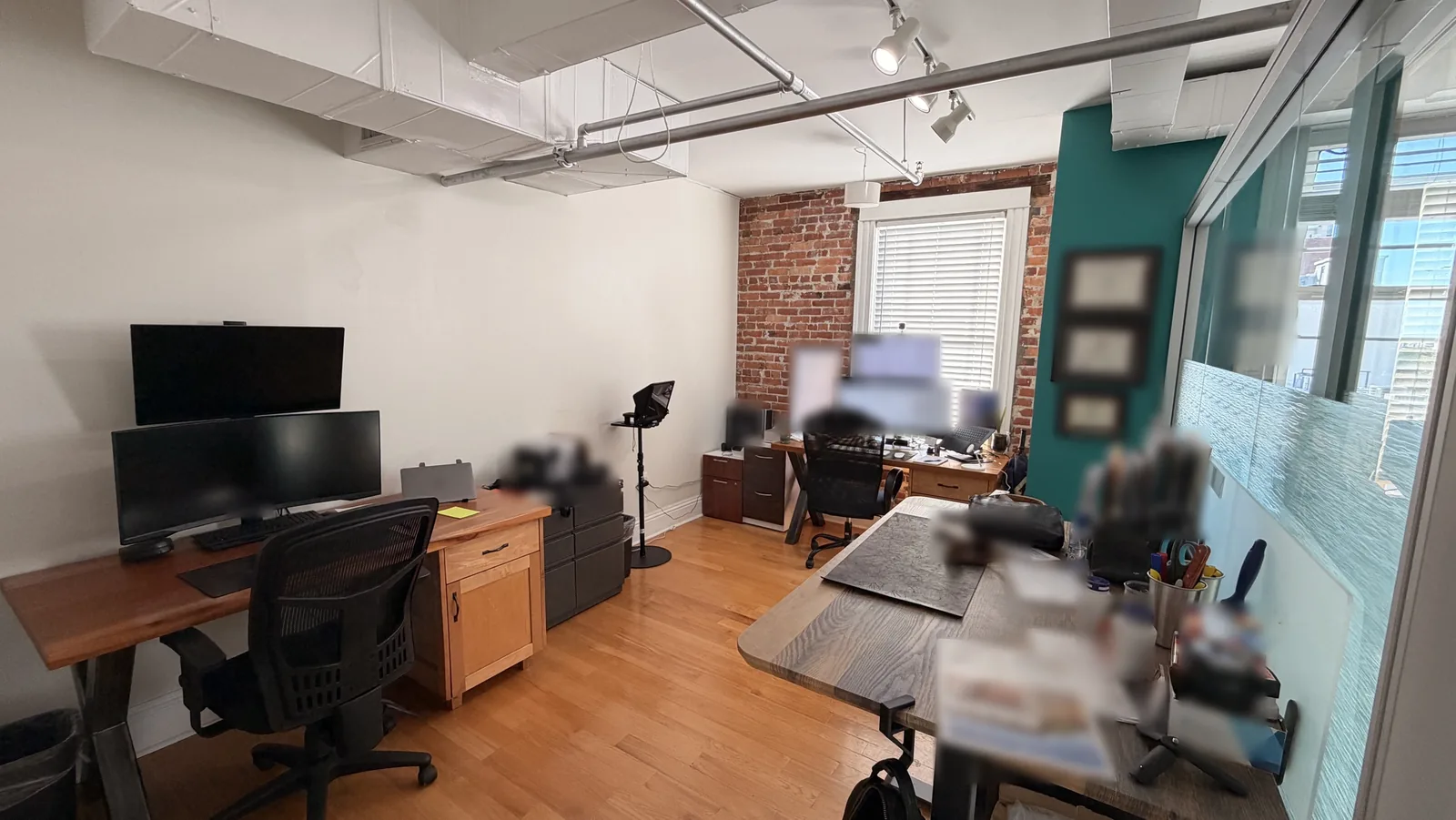 Our private office at 433 Central Ave, 4th Floor, St. Petersburg: two desks, monitors, a brick wall and a glass partition